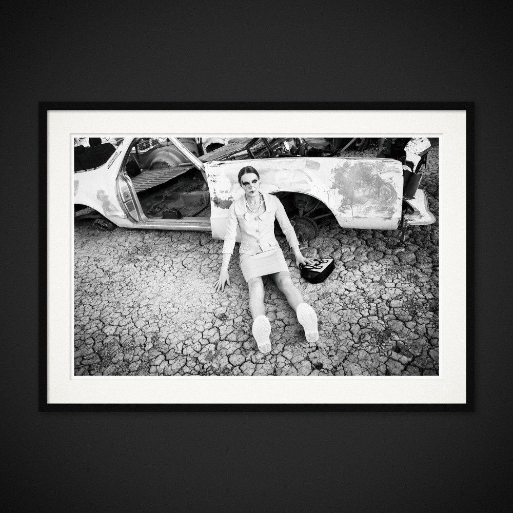 Discarded Ideals — A seated figure and a stripped car share the cracked ground. Framing preview by Albert Pocej; frame not included.