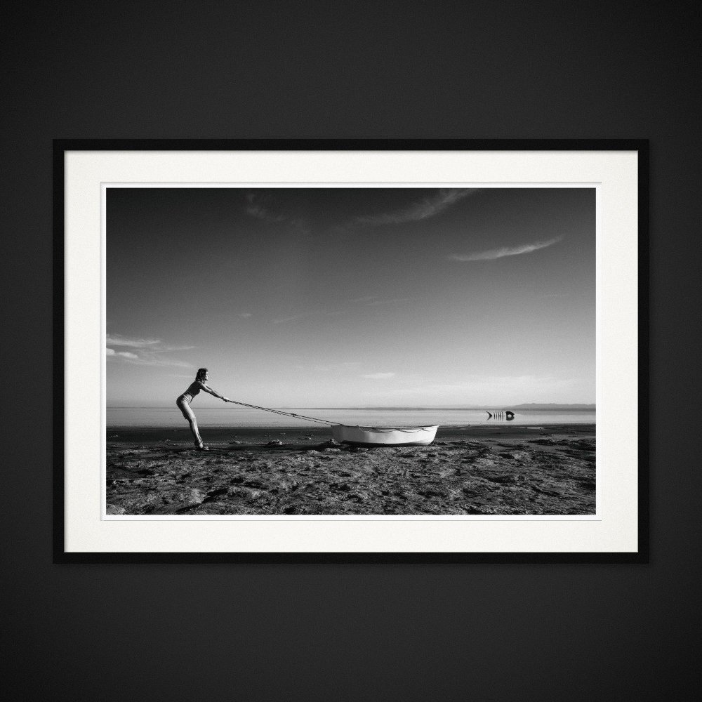 Echoes Of Rain — A small boat is pulled along the shore, opposite a fish-shaped structure. Framing preview by Albert Pocej; frame not included.