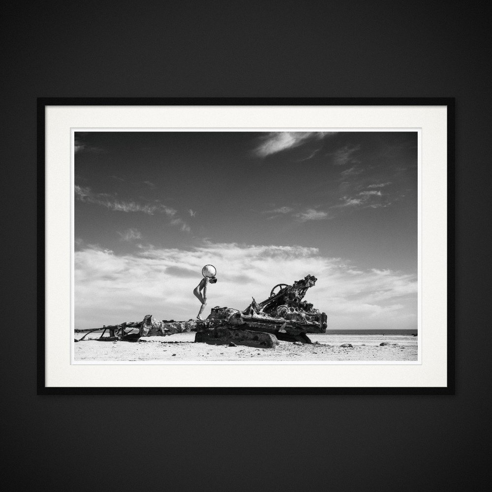 Global Pressure — A figure bends beneath a globe beside the remains of machinery. Framing preview by Albert Pocej; frame not included.