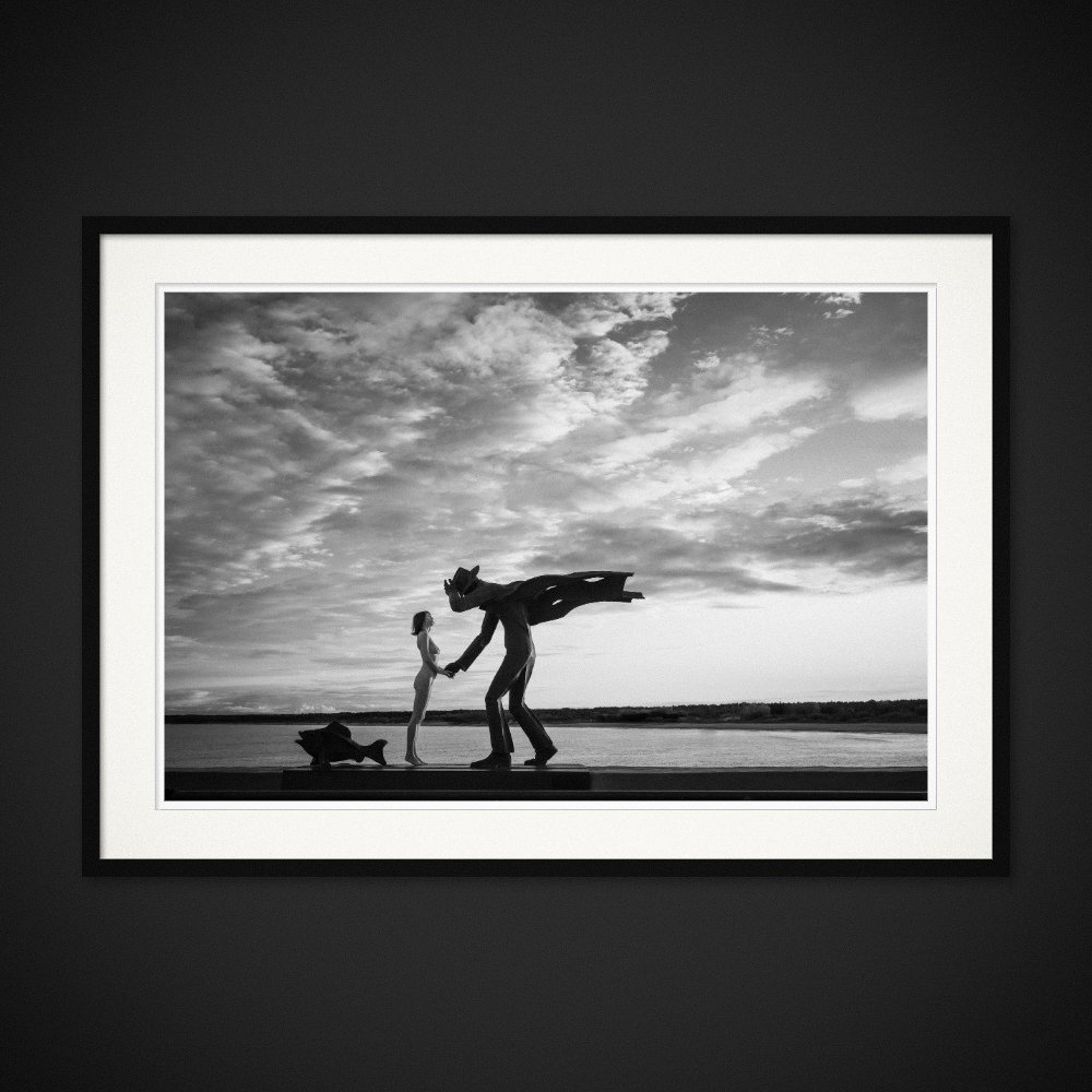 Monumental Love — A human gesture meets a much larger sculptural figure by the sea. Framing preview by Albert Pocej; frame not included.