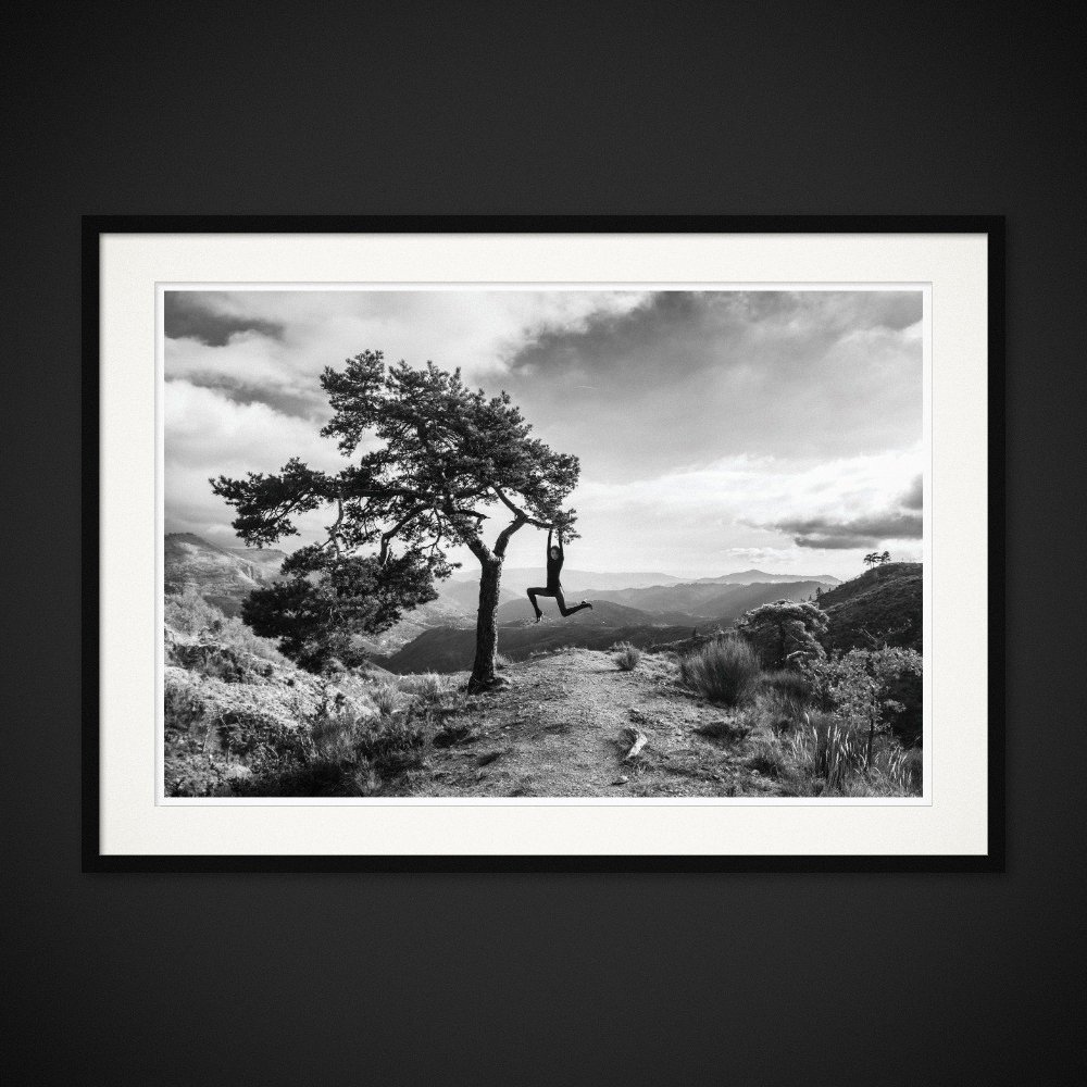 One Kilometre Of Solitude — A figure hangs from a lone tree above the mountain landscape. Framing preview by Albert Pocej; frame not included.